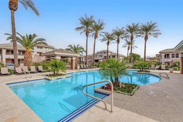 A swimming pool with lounge chairs and palm trees, surrounded by hotel buildings. - Comfortable Condo w/ Fast WiFi & Central A/C plus a Shared Pool & Hot Tub (Scottsdale)