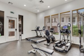 Ein Fitnessstudio mit Laufbändern, Crosstrainern und einer Trainingsbank.