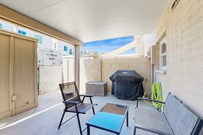Un patio couvert équipé d’un barbecue, de chaises et d’une table.