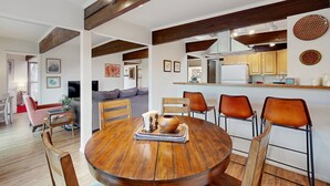 Un comedor con una mesa redonda de madera, cuatro sillas y un florero en el centro.
