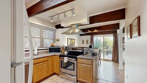 Una cocina moderna con armarios de madera, una estufa de acero inoxidable y un ventanal con persianas.