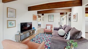Un salón moderno con televisor, sofás y una alfombra colorida.