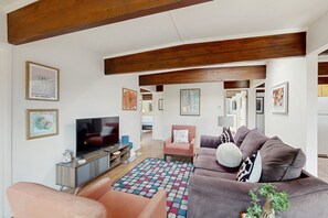 Ein modernes Wohnzimmer mit Fernseher, Sofas und einem bunten Teppich.