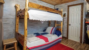 A single-occupancy room with a wooden bunk bed, a white door, and a small shelf with items. - RRR Retreat | 2 Cabins | Medina Riverfront (Medina)