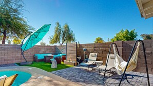 A backyard with a pool, outdoor furniture, a hammock, and a patio area. - This charming, single-level home in Chandler is the ideal spot for families (Chandler)