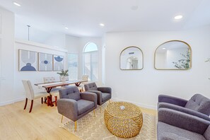 Ein modernes Wohnzimmer mit Essbereich, ausgestattet mit einem runden Couchtisch, grauen Sofas und einem Esstisch mit Stühlen.