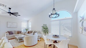 A spacious living room with a sofa set, a dining table with chairs, a chandelier, and a ceiling fan. - This charming, single-level home in Chandler is the ideal spot for families (Chandler)