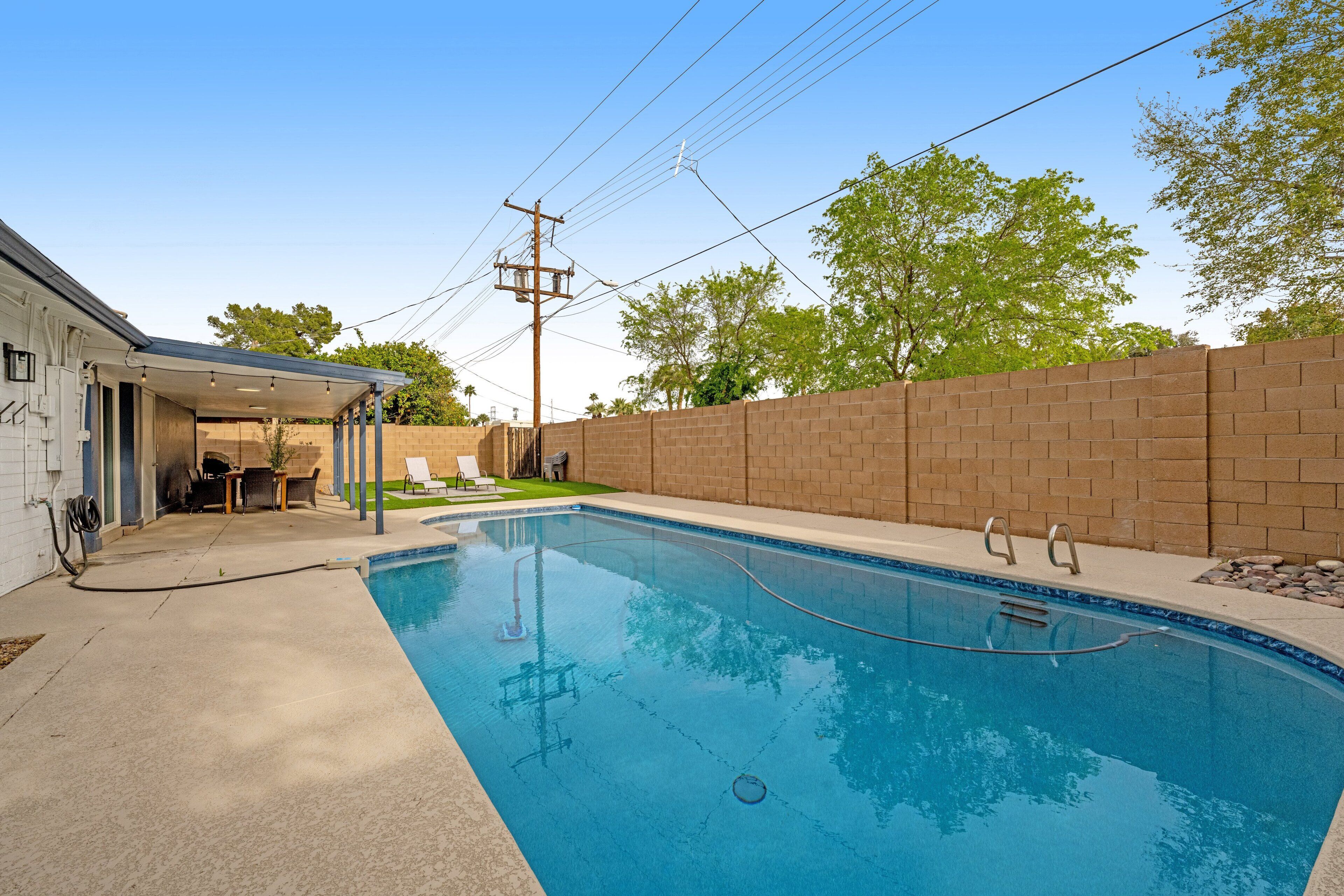 A swimming pool with a brick wall and a covered patio area.