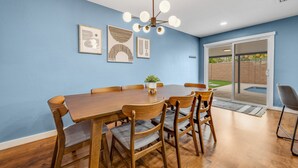 Ein Essbereich mit Holztisch und Stühlen, einer Deckenleuchte und gerahmten Bildern an der Wand.