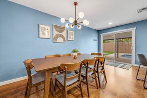 A dining area with a wooden table and chairs, a ceiling light fixture, and framed artwork on the wall. - Newly renovated house with private pool, washer/dryer, enclosed backyard, grill (Scottsdale)