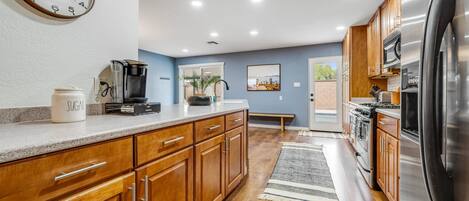 A modern kitchen with wooden cabinets, stainless steel appliances, and a coffee maker on the counter.