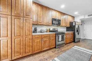 A kitchen with wooden cabinets, stainless steel appliances, and a tiled backsplash. - Newly renovated house with private pool, washer/dryer, enclosed backyard, grill (Scottsdale)