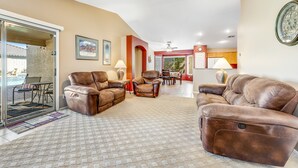 A spacious living room with leather sofas, a ceiling fan, and a view of the outside.