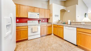 A kitchen with wooden cabinets, a microwave, an oven, and a dishwasher.