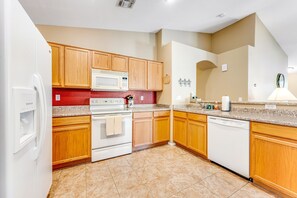 A kitchen with wooden cabinets, a microwave, an oven, and a dishwasher.
