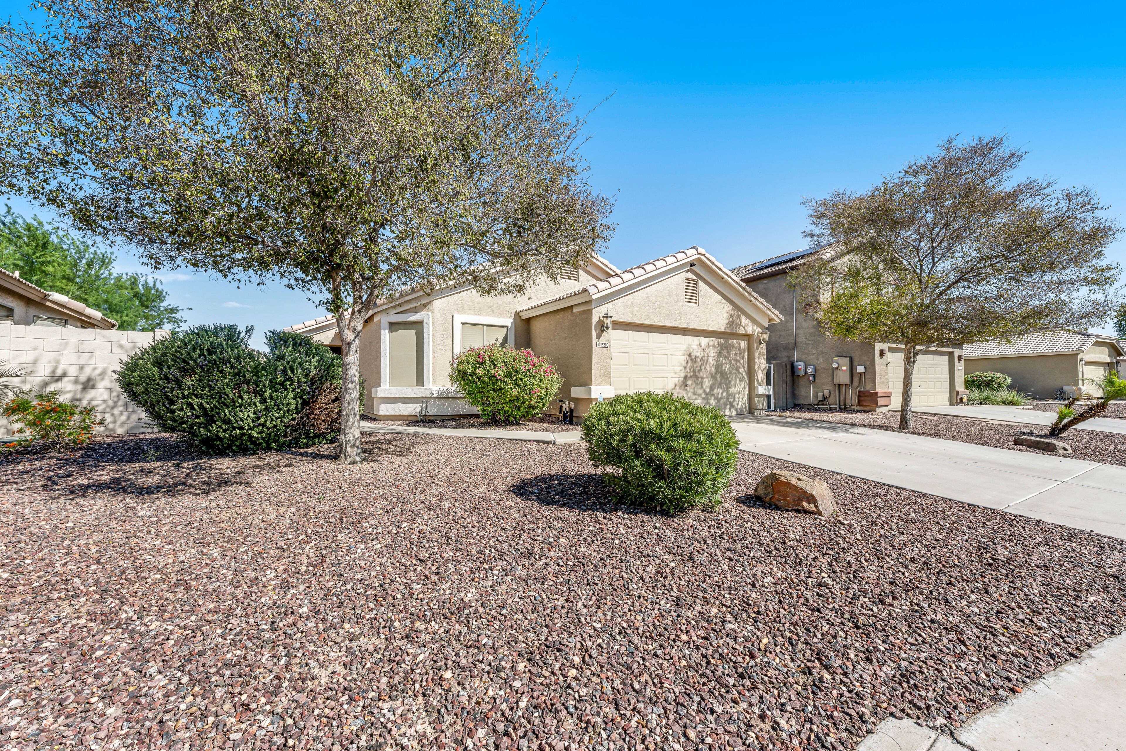 A residential area with houses, gravel landscaping, and trees.