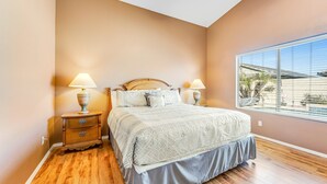 A bedroom with a bed, nightstands, and a window with blinds.