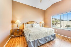 A bedroom with a bed, nightstands, and a window with blinds.