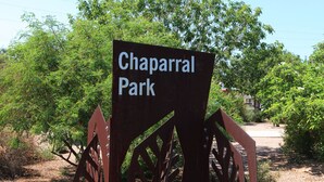Schild für Chaparral Park mit einem Metalltor und Grünanlagen im Hintergrund.