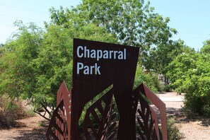 Schild für Chaparral Park mit einem Metalltor und Grünanlagen im Hintergrund.