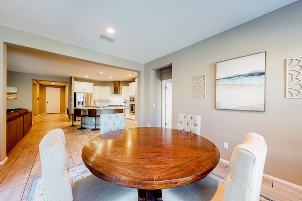 A spacious dining area with a large wooden table and four upholstered chairs.