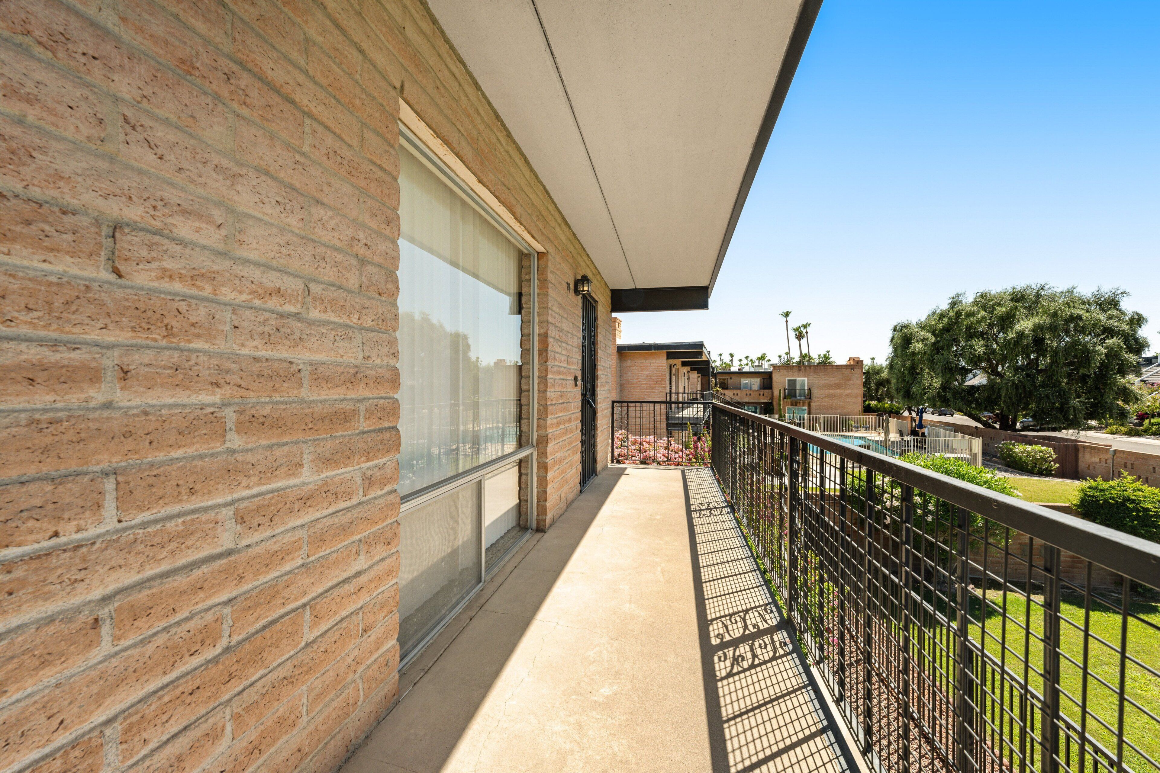 A brick building with a balcony, a glass door, and a metal railing.