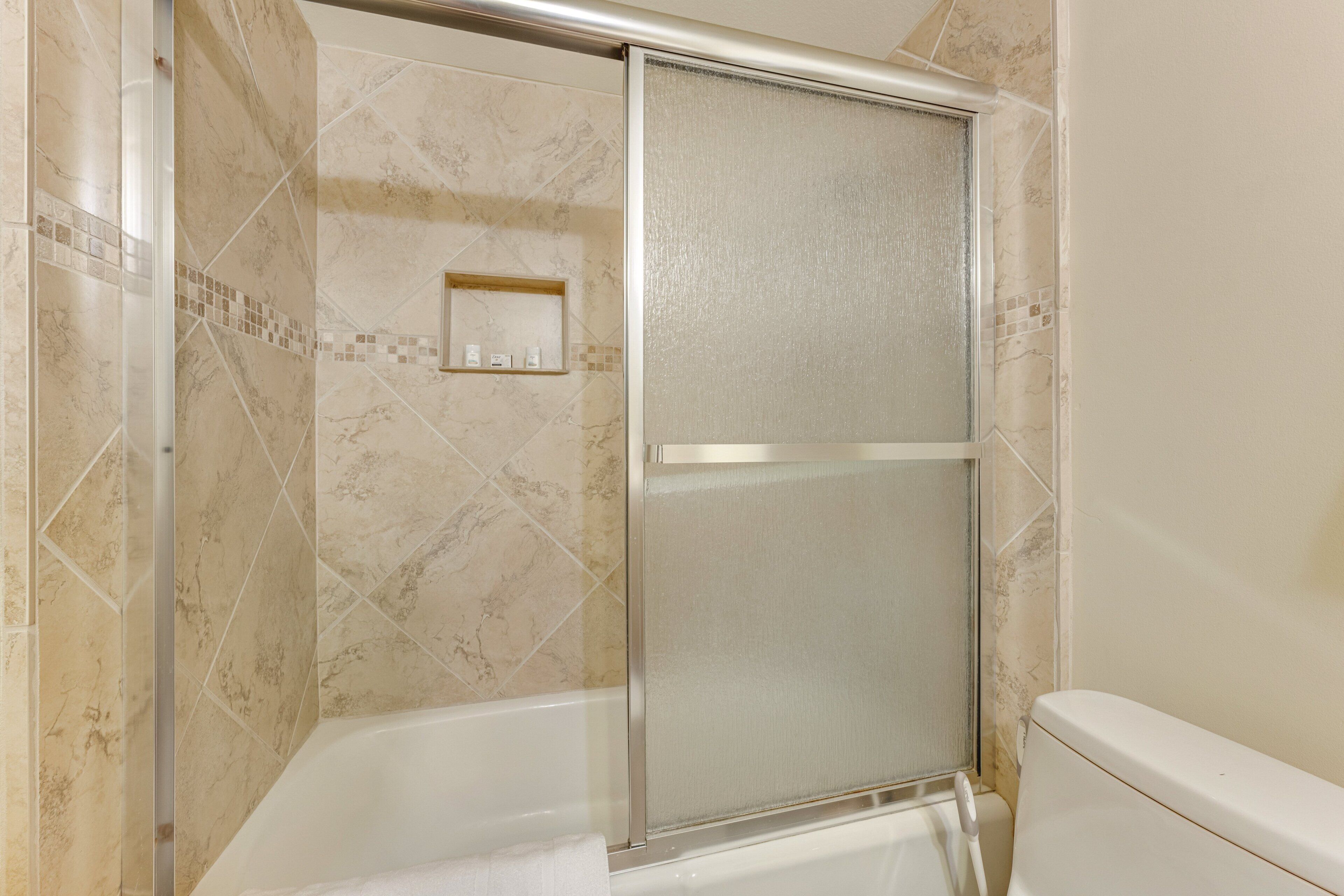 Een badkamer met een douche met glazen wanden, een bad en een toilet.
