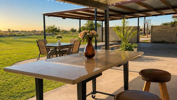 Une terrasse extérieure avec une table, des chaises et des tabourets.