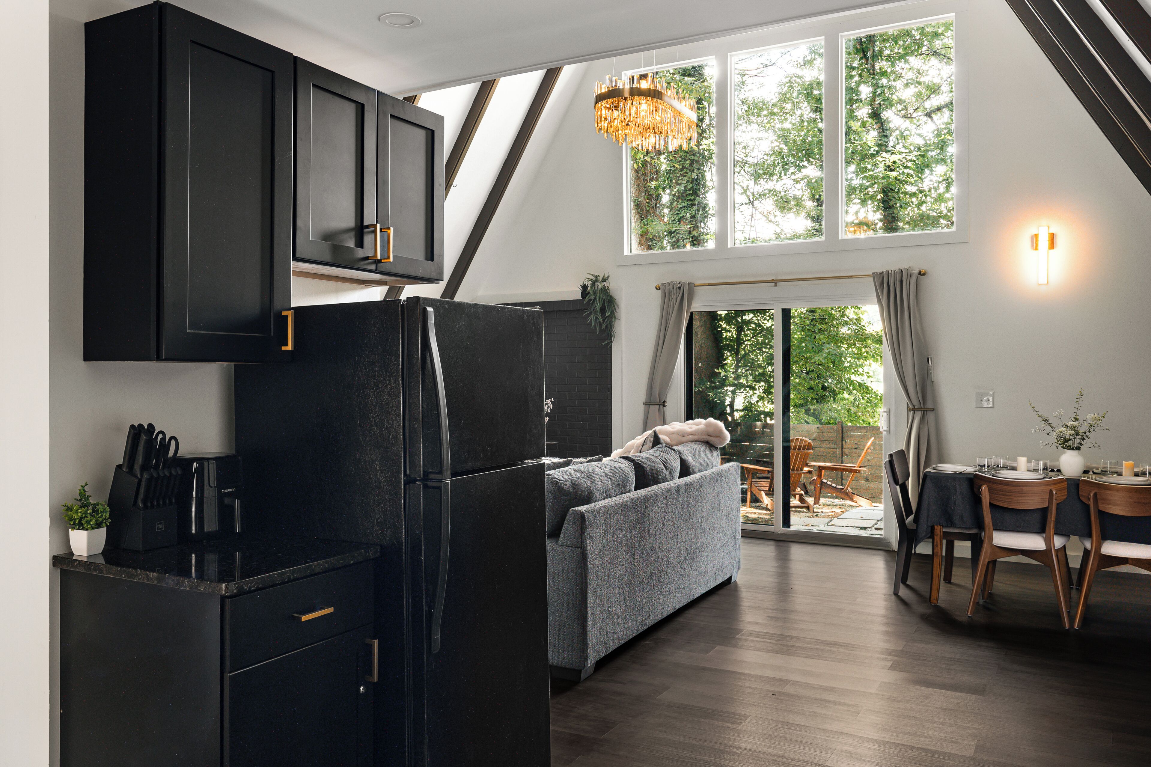 A modern kitchen with a black refrigerator, wooden cabinets, and a dining area with a table set for two.