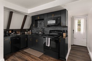 A modern kitchen with black cabinetry, a built-in microwave, a stove, and a dishwasher.