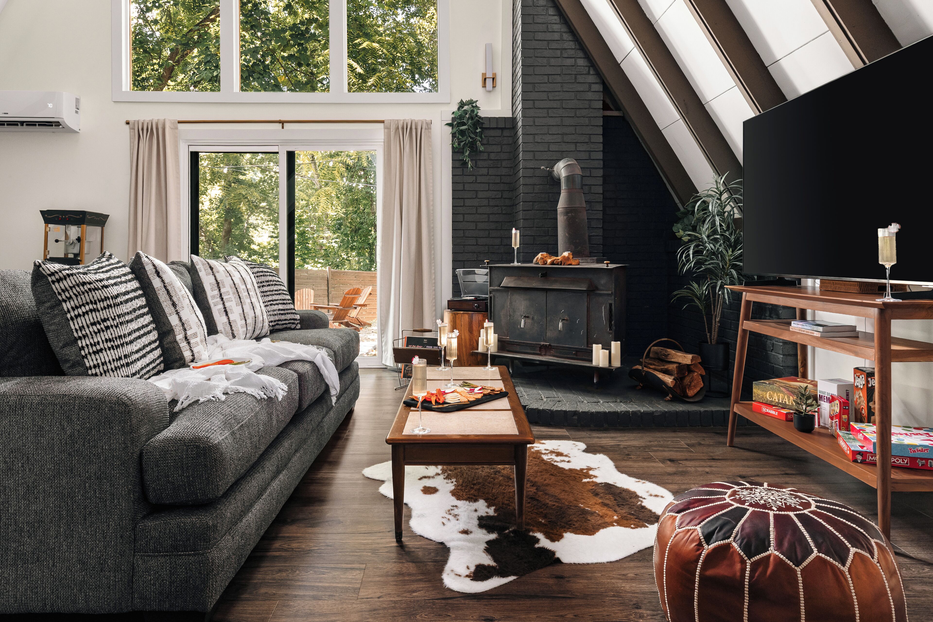 Een moderne woonkamer met een grijze bank, een houten salontafel, een zwarte open haard en een boekenkast.
