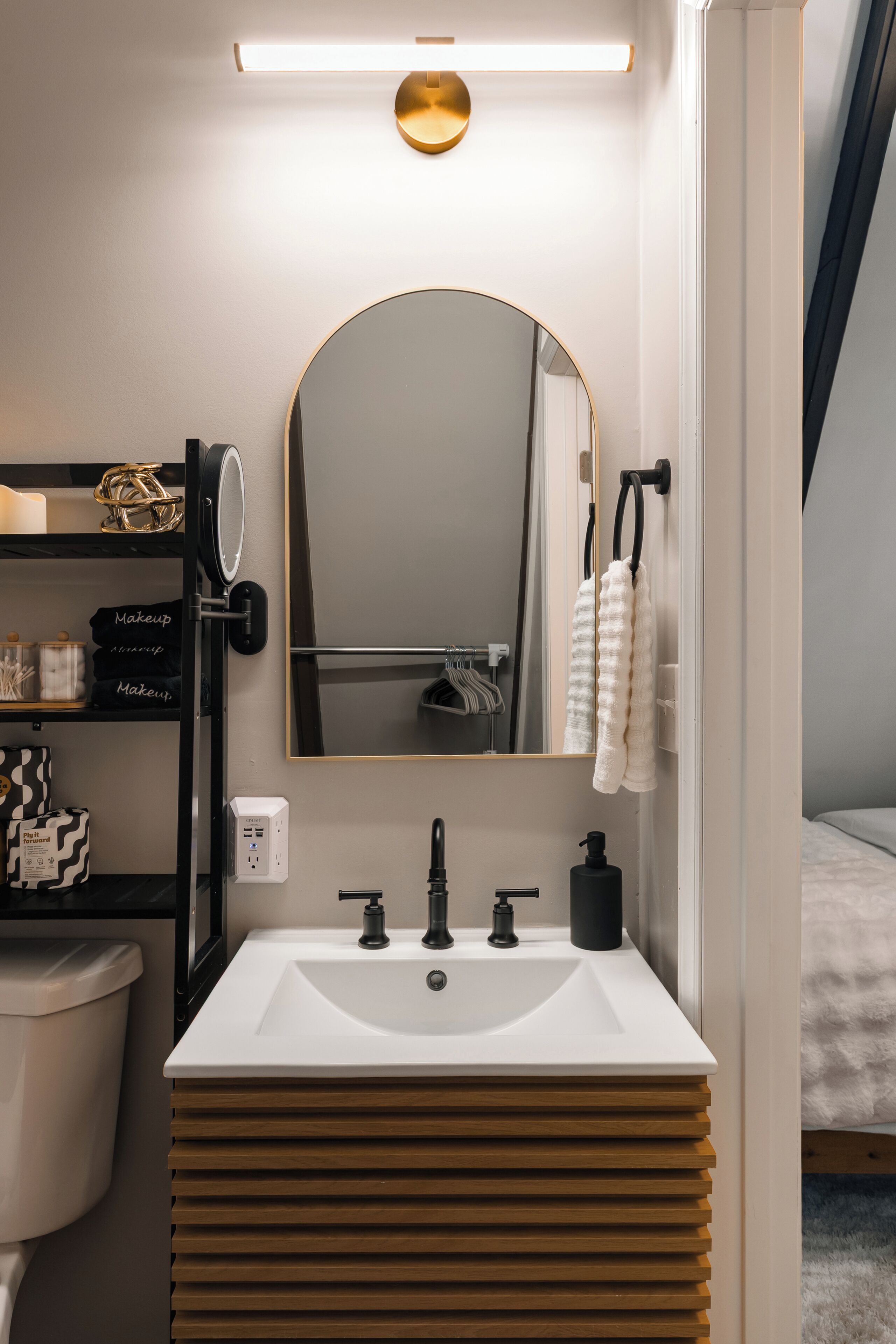 A modern bathroom with a white sink, black faucets, and a large mirror.
