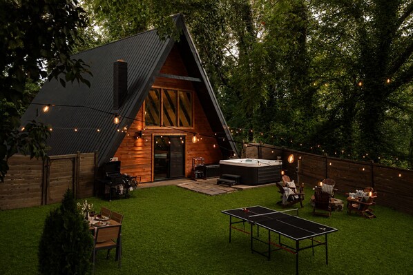 Un espacio exterior acogedor con jacuzzi, mesa de ping pong y asientos.