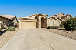 A residential house with a beige facade, a garage, and a driveway leading to the entrance.