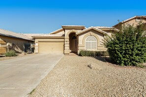 A residential house with a garage, a driveway, and a well-maintained gravel lawn.