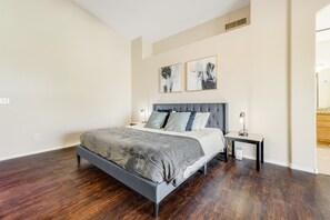A modern bedroom with a large bed, a nightstand, and two abstract paintings on the wall. - Modern Home w/ Private Pool, Central AC, WiFi, Private W/D, & Private Gas Grill (Goodyear)