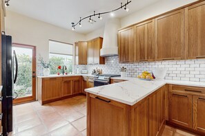 Uma cozinha com armários de madeira, uma ilha de mármore branco e um forno embutido.