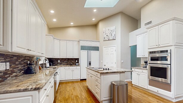 A modern kitchen with white cabinets, a granite countertop, a built-in oven, and a skylight. - Your Perfect Family Escape in Sunny Peoria – Private Pool and Relaxation Awaits (Peoria)