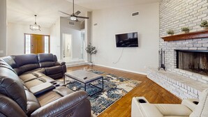 A modern living room with a sectional sofa, a fireplace, a flat-screen TV, and a ceiling fan. - Your Perfect Family Escape in Sunny Peoria – Private Pool and Relaxation Awaits (Peoria)