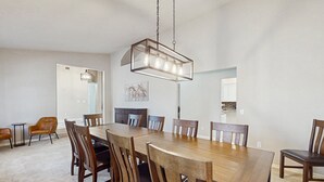 A dining room with a large wooden table, six chairs, and a hanging light fixture. - Your Perfect Family Escape in Sunny Peoria – Private Pool and Relaxation Awaits (Peoria)