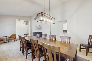 A dining room with a large wooden table, six chairs, and a hanging light fixture. - Your Perfect Family Escape in Sunny Peoria – Private Pool and Relaxation Awaits (Peoria)
