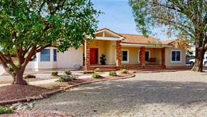 A two-story house with a brick facade, a red door, and a porch with a swing. - Your Perfect Family Escape in Sunny Peoria – Private Pool and Relaxation Awaits (Peoria)