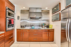 A modern kitchen with stainless steel appliances, wooden cabinets, and a granite countertop. - Pleasant & modern dog-friendly home w/ private pool spa & heated outdoor pool (Palm Springs)