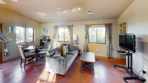 Ein Wohnzimmer mit einer Couch, Sesseln, einem Tisch, einem Fernseher und einem Deckenventilator.