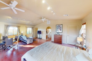 Une chambre d’hôtel équipée d’un lit, d’un bureau, d’une chaise, d’une télévision, d’une armoire et d’un ventilateur de plafond.