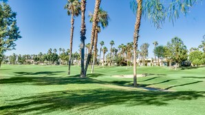 Ein Golfplatz mit Palmen, einem Sandbunker und blauem Himmel.