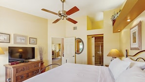 A hotel room with a bed, a television, a dresser, and a ceiling fan. - Classic and comfortable condo with pool, hot tub, & tennis (Tucson)