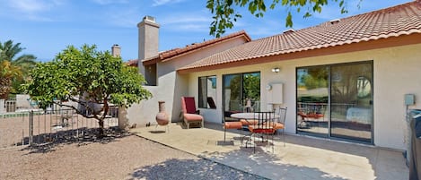 A house with a patio, a large window, and a tree.