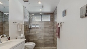 A modern bathroom with a glass shower enclosure, a toilet, and a sink. - Dog friendly condo w/two patios & shared pool/tennis - walk downtown (Palm Springs)