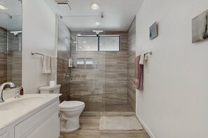 Ein modernes Badezimmer mit Duschkabine aus Glas, Toilette und Waschbecken.